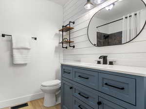 Bathroom featuring vanity, light wood-type flooring, wooden walls, and a shower with shower curtain