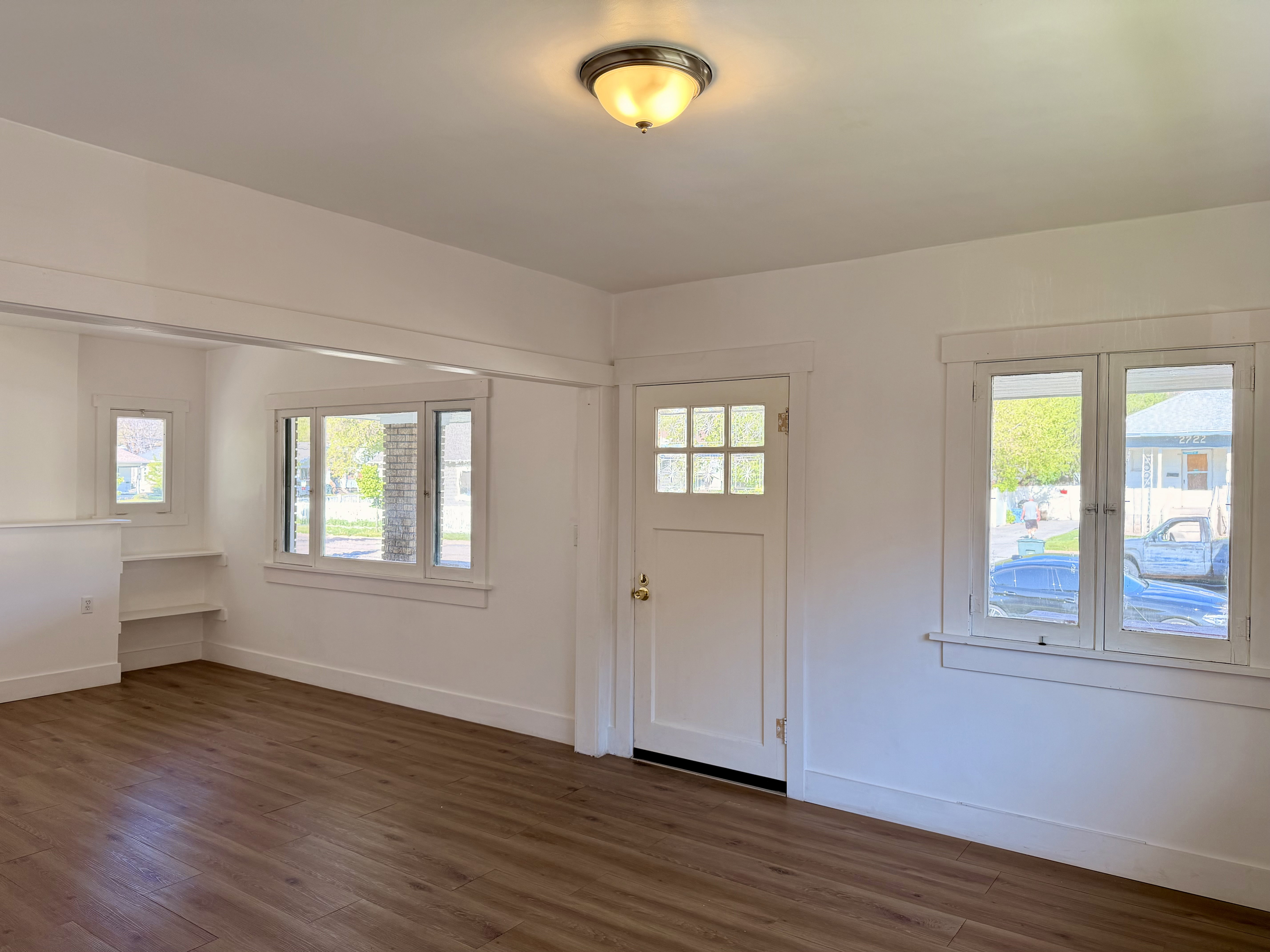 Entryway featuring wood-finish flooring, white trim, recessed built-in shelving, a multi-pane entry door, and multiple windows