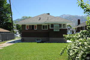 Rear view of property featuring a mountain view, brick siding, and roof with shingles