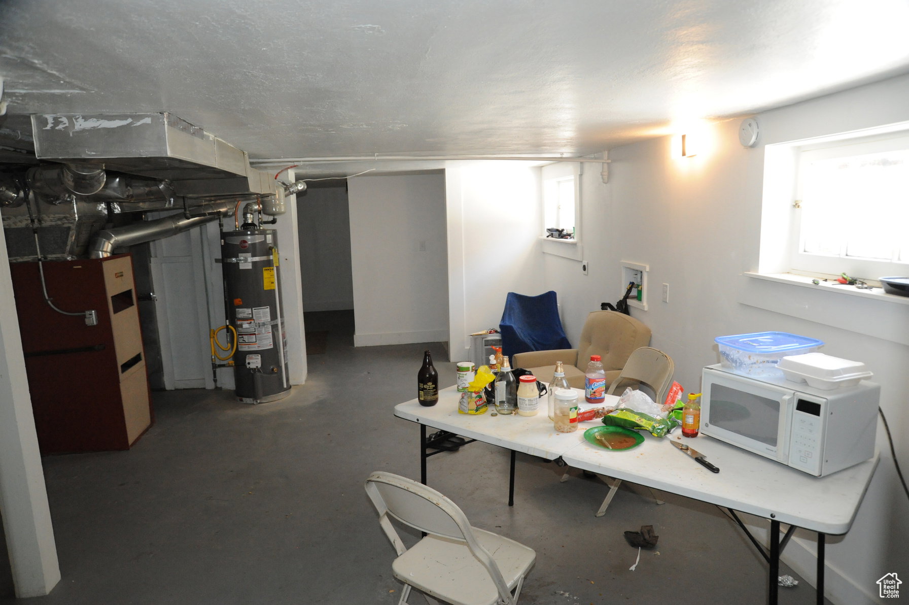 Basement featuring strapped water heater, heating unit, and healthy amount of natural light