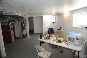 Basement featuring strapped water heater, heating unit, and healthy amount of natural light