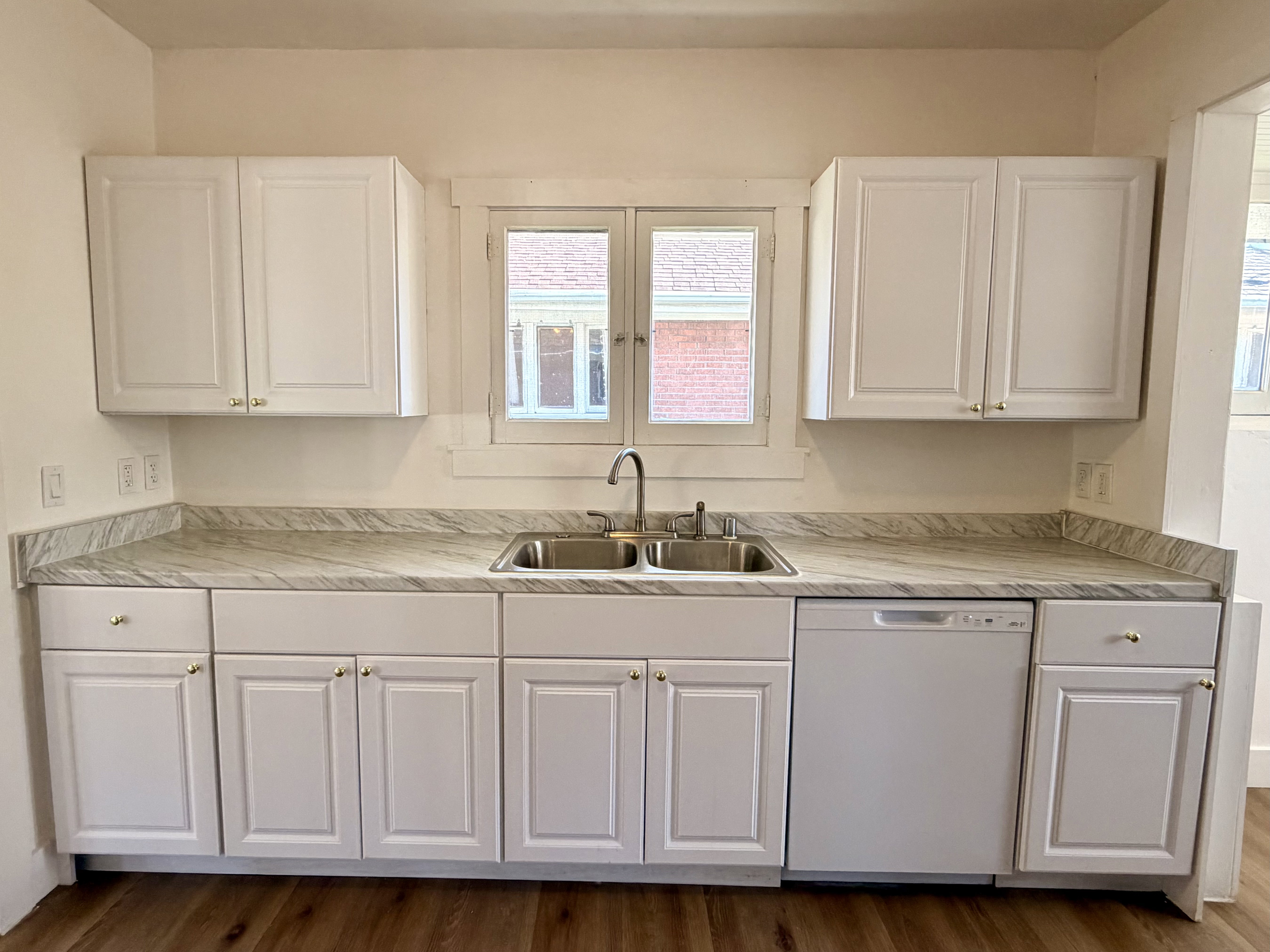 Kitchen featuring white cabinetry, a double basin stainless steel sink, a white dishwasher, and wood-finish flooring