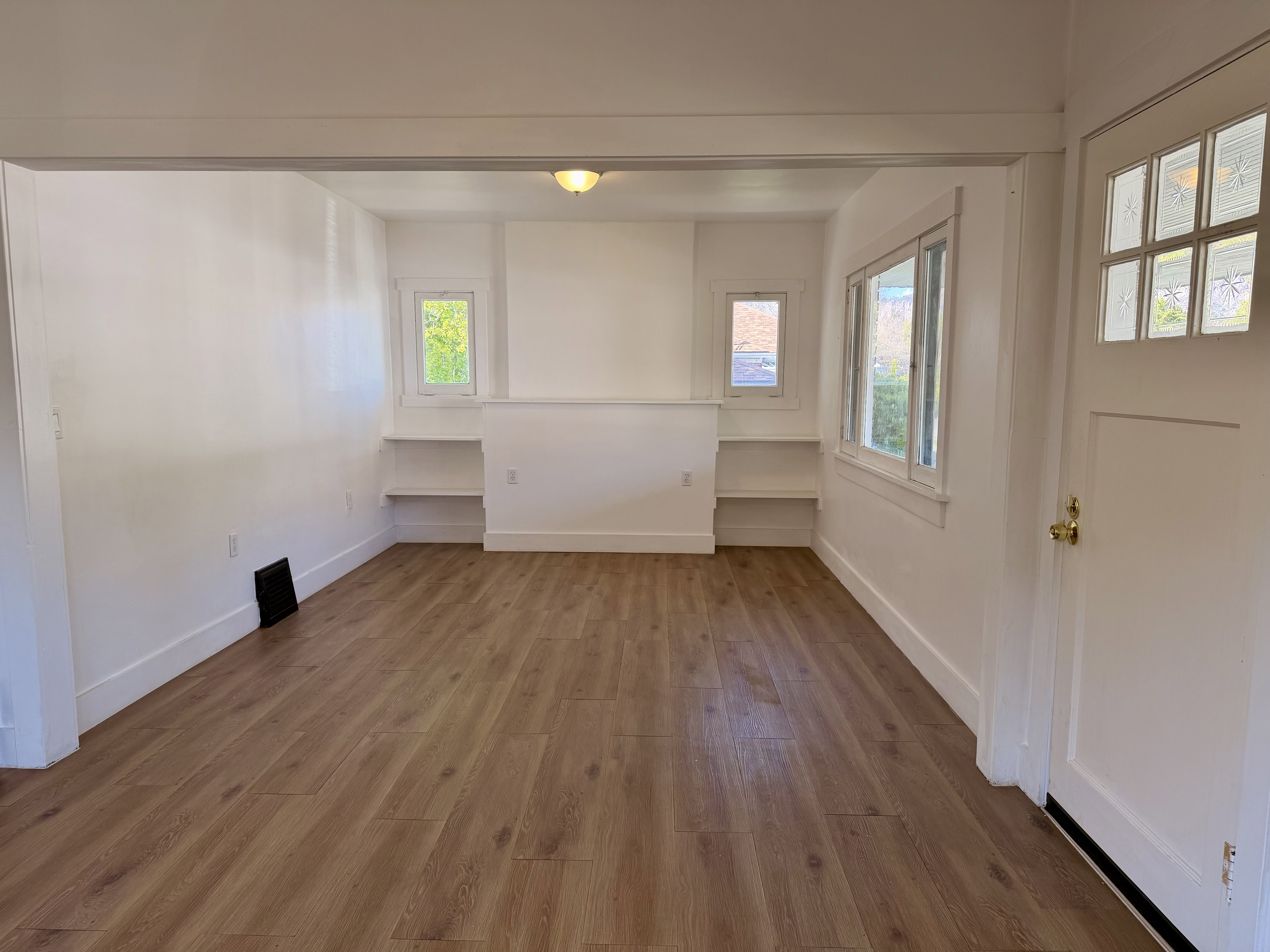 Open concept living space featuring wood-finish flooring, multiple windows, and built-in shelving