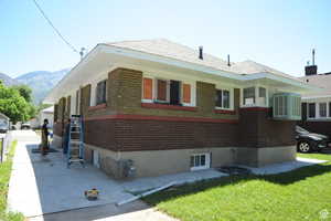 View of home's exterior featuring brick siding, a yard, and a mountain view