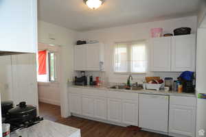 Kitchen featuring light countertops, white dishwasher, healthy amount of natural light, and dark wood-type flooring