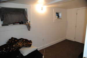 Bedroom featuring dark colored carpet and baseboards