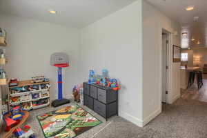 Recreation room with light colored carpet and recessed lighting