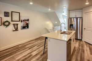Kitchen featuring stainless steel appliances, a breakfast bar area, a kitchen island with sink, recessed lighting, and light wood-style floors