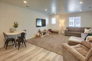 Living area with light wood-type flooring and recessed lighting