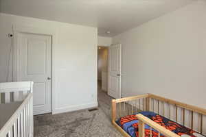 Bedroom featuring a crib and dark carpet