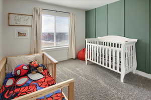 Carpeted bedroom featuring a crib