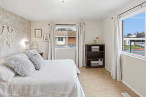 Primary bedroom with light wood finished floors and multiple windows