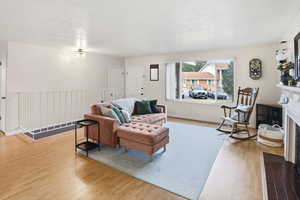 Living area featuring a fireplace with flush hearth, light wood-style flooring, and a textured ceiling