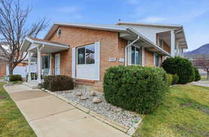 View of home's exterior with brick siding, a lawn, and a porch