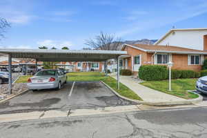 View of front of property with a front yard, brick siding, covered parking, and a mountain view