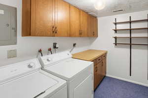 Laundry area featuring cabinet space, a textured ceiling, electric panel, independent washer and dryer, and dark carpet