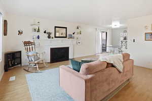 Living room featuring a fireplace with flush hearth and light wood-style flooring