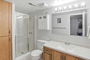 Full bathroom with a stall shower, vanity, and a textured ceiling