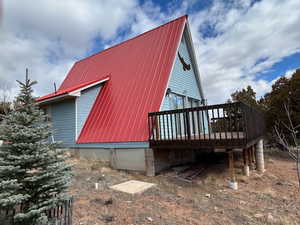 View of side of home featuring a wooden deck and a metal roof