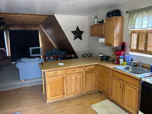 Kitchen featuring a peninsula, light countertops, light wood-type flooring, open floor plan, and range with electric stovetop