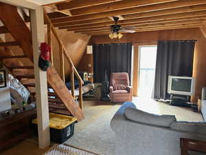 Living area featuring wood walls, a ceiling fan, and carpet floors