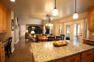 Kitchen with light stone counters, wood finish cabinets, an office area, open floor plan, and a kitchen island