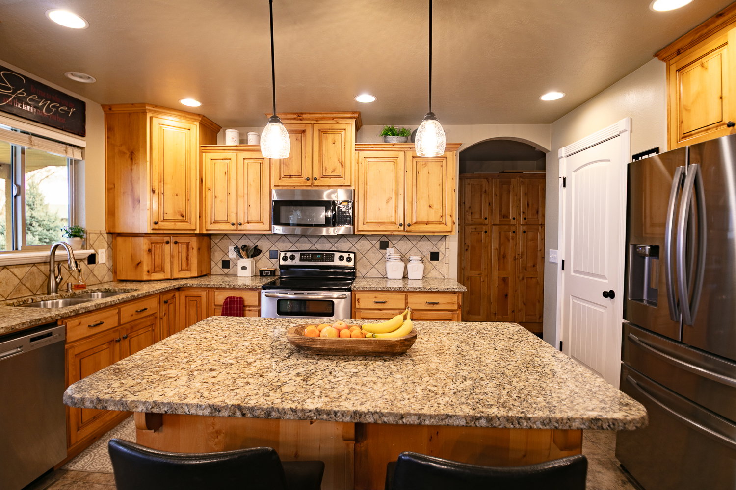 Kitchen featuring stainless steel appliances, light stone counters, a kitchen island, a breakfast bar, and pendant lighting