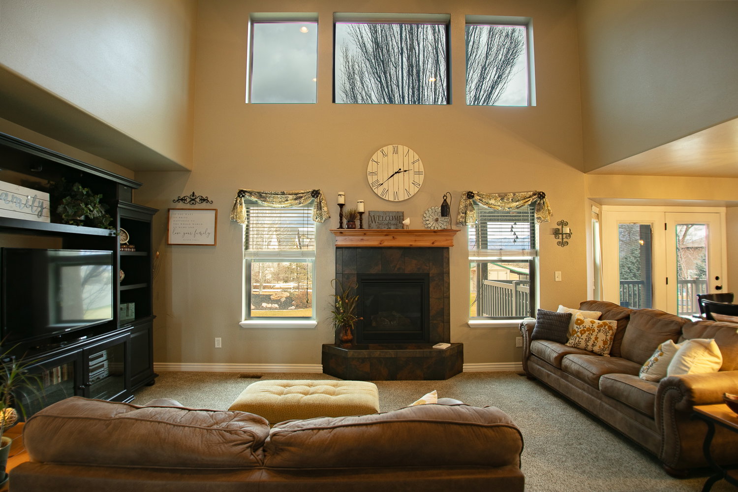 Carpeted living room featuring a tiled gas fireplace, healthy amount of natural light, and vaulted ceiling