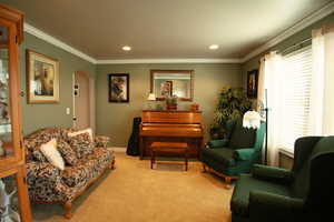 Living room featuring arched doorways, crown molding, carpet floors, recessed lighting with a large West facing window.