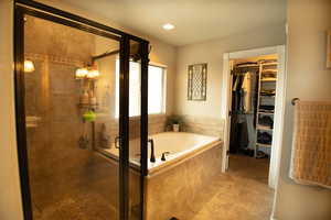 Full bathroom featuring a stall shower, a jetted tub, a spacious walk-in closet, light tile patterned floors, and recessed lighting
