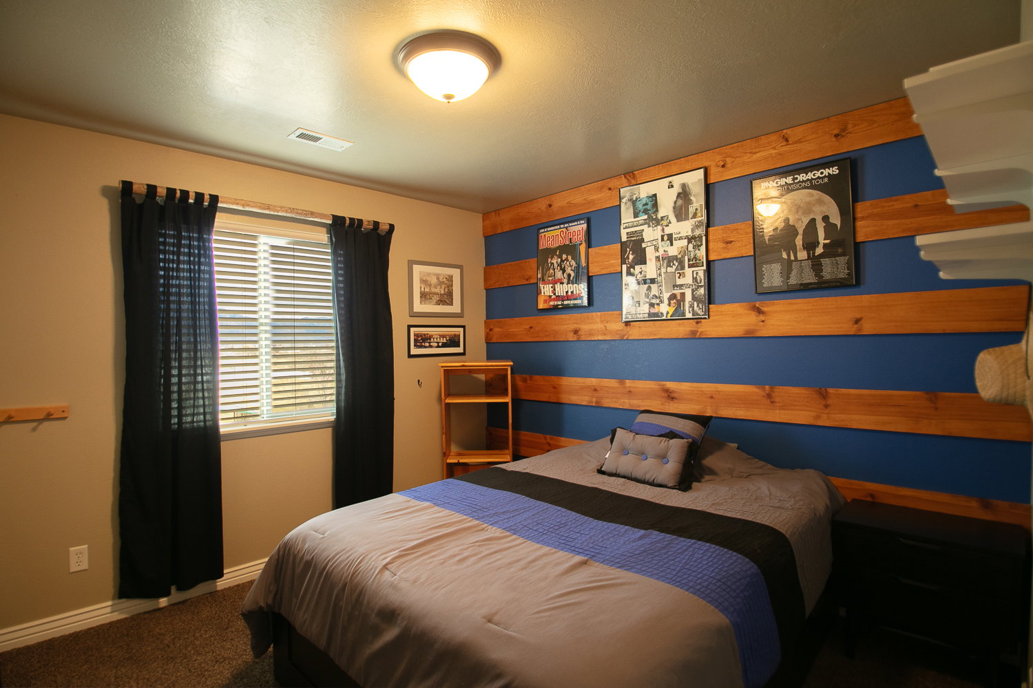 Upstairs bedroom with carpeted floors and an accent wall with rustic wooden planks.