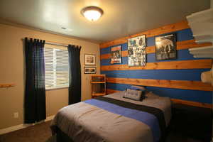 Upstairs bedroom with carpeted floors and an accent wall with rustic wooden planks.