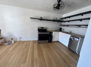 Kitchen featuring open shelves, stainless steel appliances, white cabinets, a textured ceiling, and light wood-style flooring