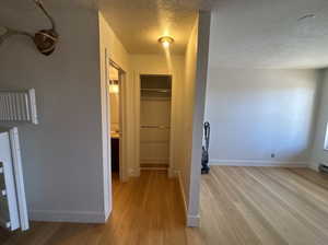 Hallway featuring a textured ceiling and light wood-type flooring