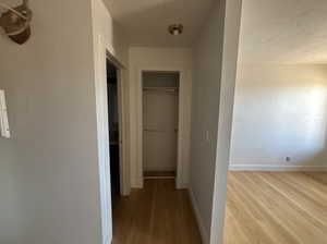 Hallway with light wood-style flooring and a textured ceiling