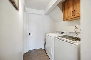 Laundry room featuring dark colored carpet, cabinet space, and washer and clothes dryer