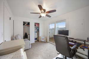 Office area featuring light colored carpet, a baseboard radiator, electric panel, and a ceiling fan