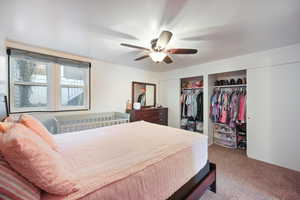 Bedroom featuring carpet flooring, a ceiling fan, and multiple closets