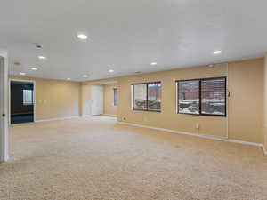 Empty room with light colored carpet and recessed lighting