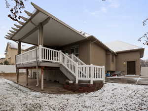 Snow covered back of property with a patio area and a deck