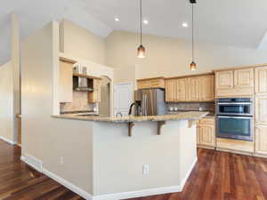 Kitchen with tasteful backsplash, light wood finish cabinetry, a breakfast bar, stainless steel appliances, and light stone countertops