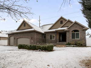 View of front facade featuring a garage, stone siding, stucco siding, and driveway