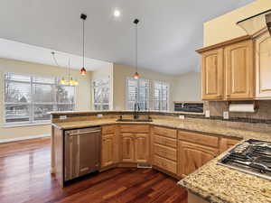 Kitchen featuring stainless steel appliances, a peninsula, lofted ceiling, backsplash, and light stone countertops
