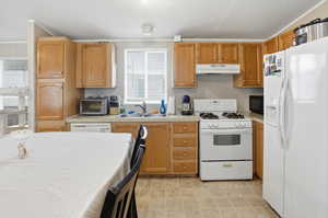Kitchen with white appliances, light countertops, ornamental molding, and a textured ceiling