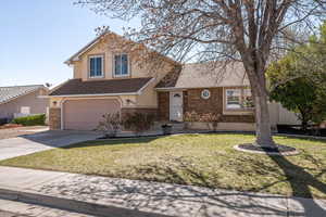 Traditional-style house featuring roof with shingles, a garage, driveway, brick siding, and stucco siding