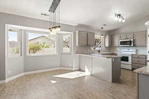 Kitchen with white range with electric cooktop, light countertops, a peninsula, gray cabinetry, and decorative backsplash