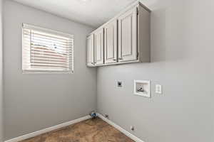 Laundry area featuring hookup for a gas dryer, cabinet space, washer hookup, electric dryer hookup, and a textured ceiling