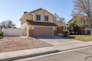 Traditional-style house with a gate, driveway, a shingled roof, a garage, and brick siding