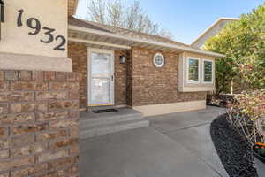 Doorway to property featuring brick siding and a shingled roof