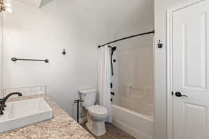 Full bath with shower / bathtub combination with curtain, light wood-style flooring, and vanity